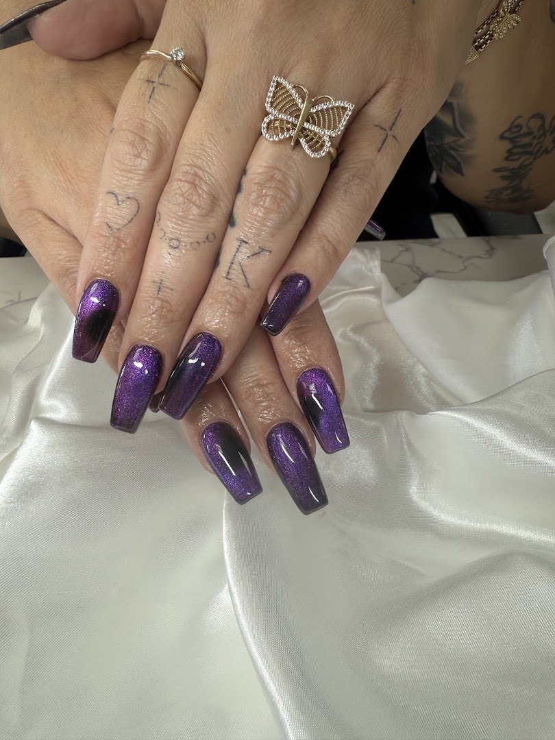 Nail technician shaping acrylic nails at a salon table.